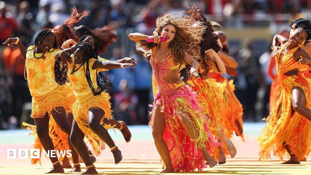 Shakira, Madonna, Justin Bieber and BTS perform at colourful World Cup half-time show Graphic representing sunshine with blue sky behind