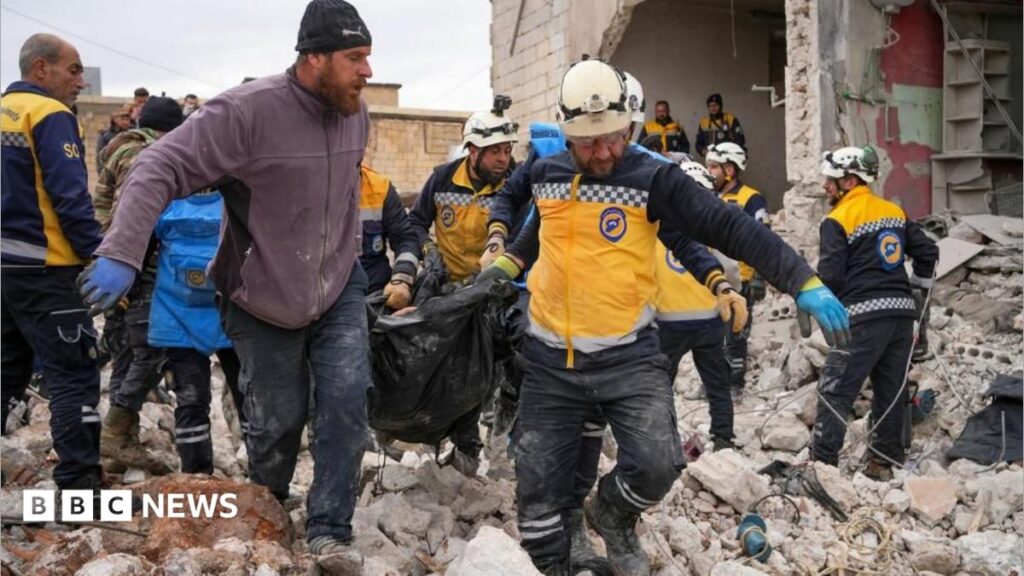 Rescuers carry a body bag across rubble