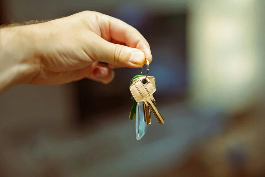 Mexico’s tenant law for foreigners: A guide to your rights Image of a hand holding a set of golden keys on a keychain. The background image is bokeh.