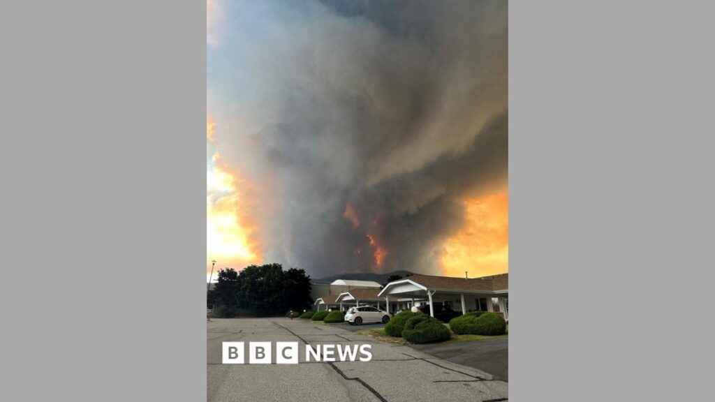 Smoke rises from the Bald Range wildfire over a residential street in Summerland
