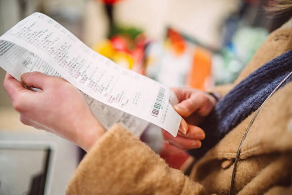 Woman reviewing shopping receipt after grocery purchase