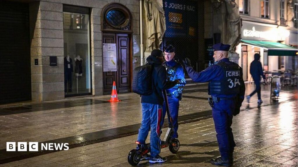 French police officers check a person during a partial curfew in Lyon on October 19