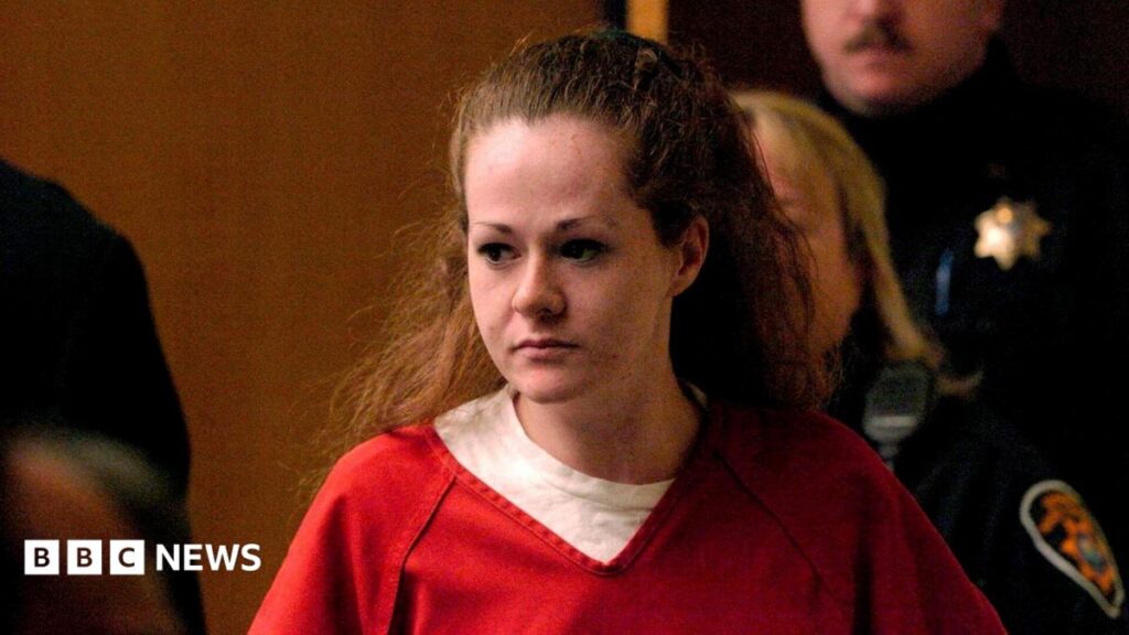 A woman with red hair wears a red jumpsuit